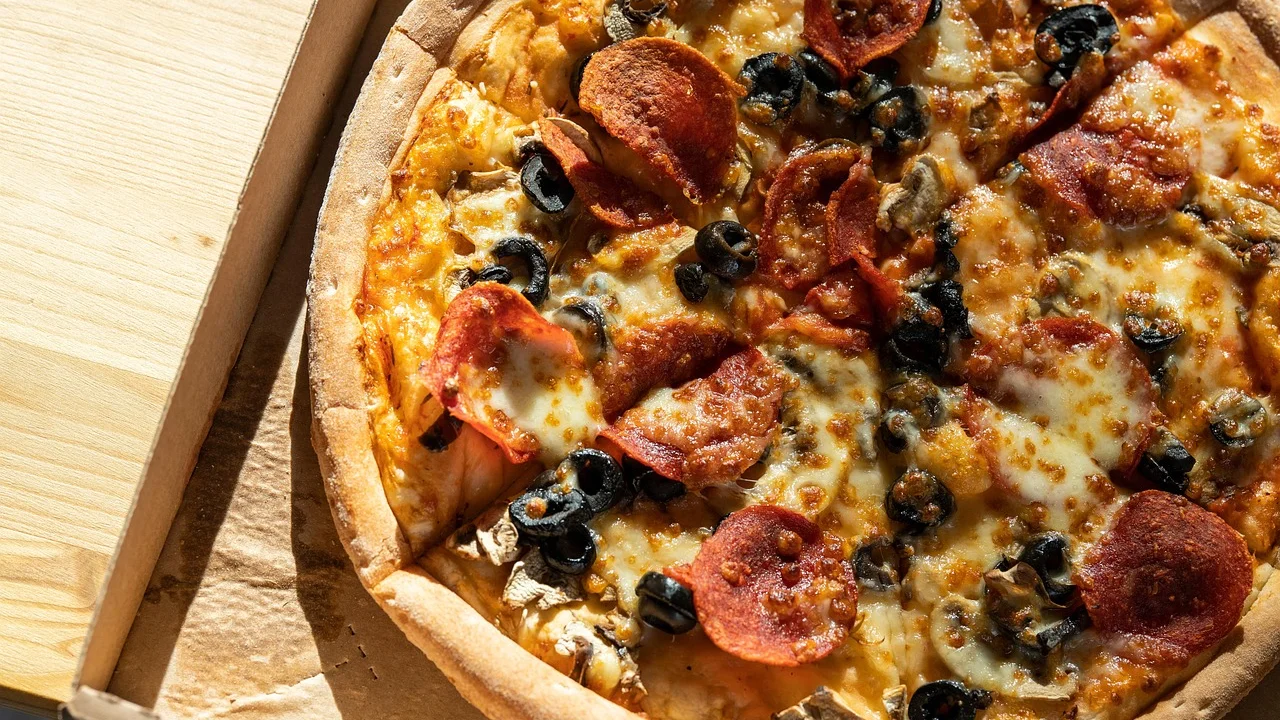 Disco de pizza aberto sobre bancada levemente enfarinhada.