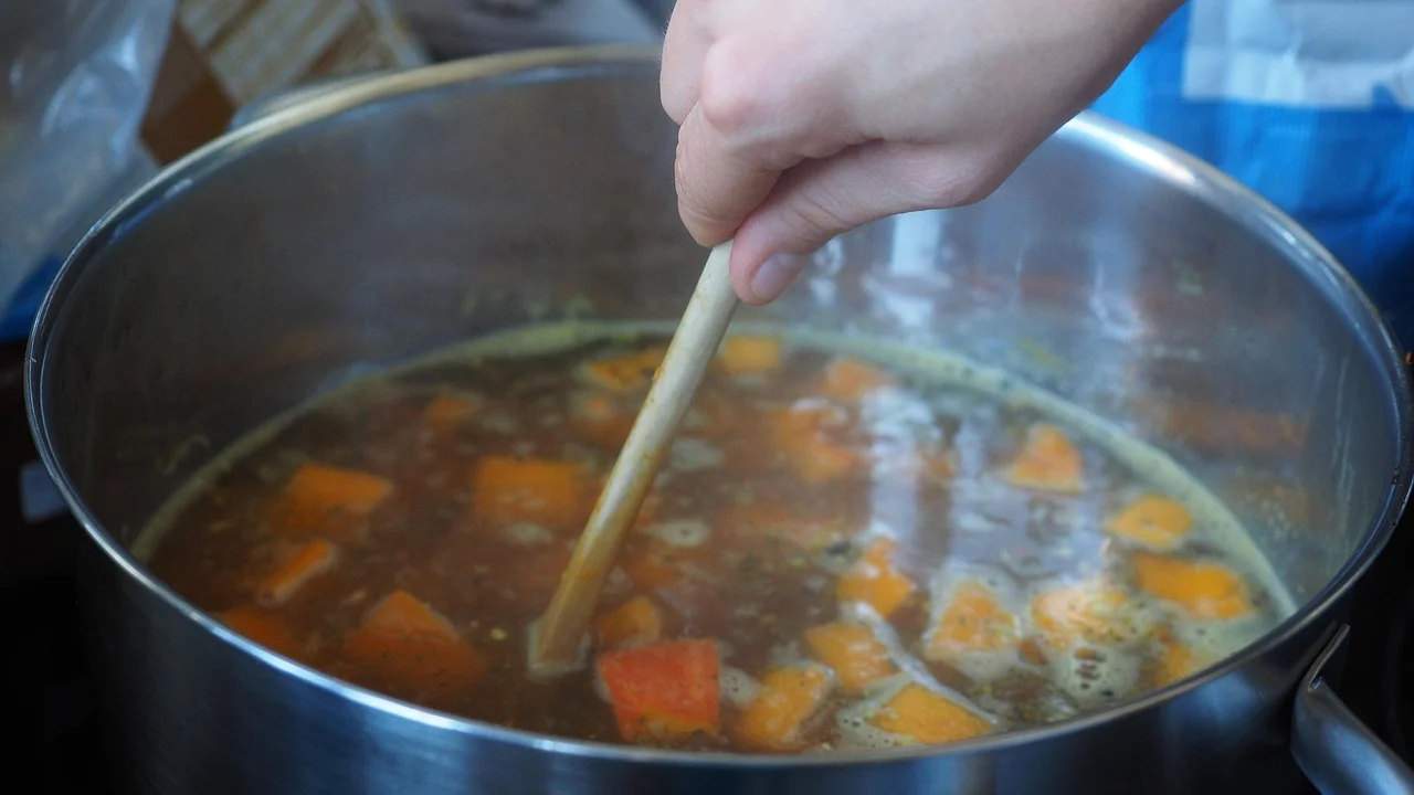 Caldo de legumes caseiro fervendo suavemente em panela ampla.