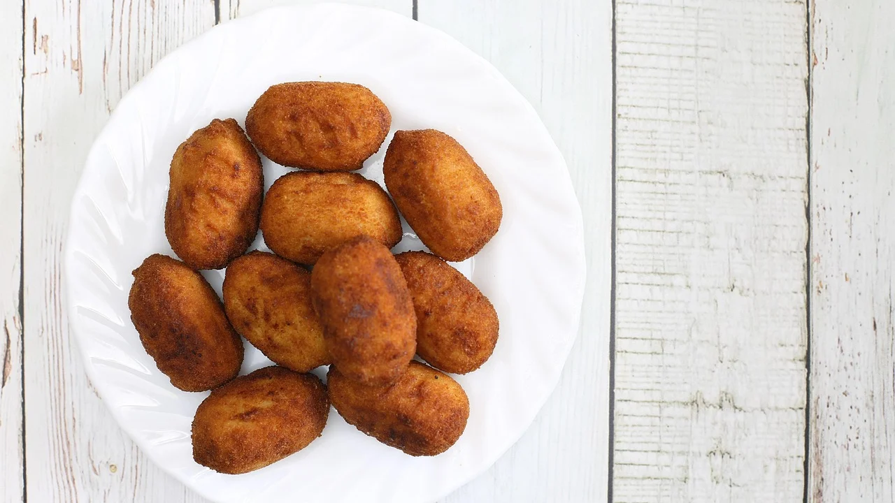Massa de coxinha sendo aberta na palma da mão para receber o recheio.