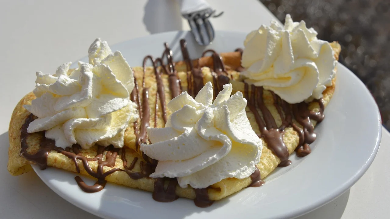 Crepes doces finos empilhados sobre um prato claro.