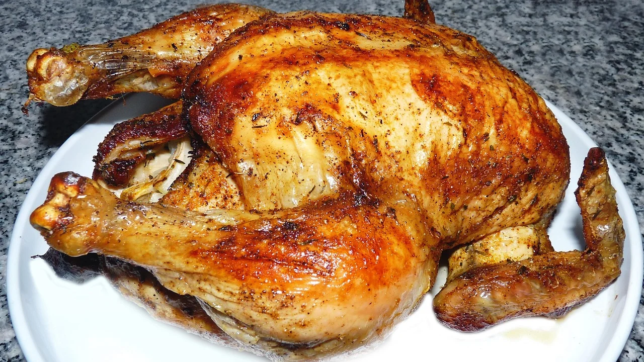 Frango inteiro temperado pronto para entrar no forno.