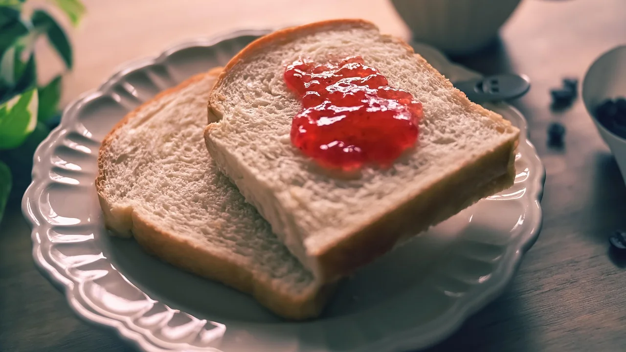 Torradas com geleia de morango em uma mesa de café da manhã.