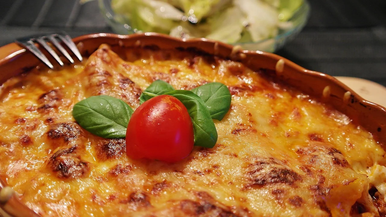 Lasanha caseira servida com salada de folhas frescas.