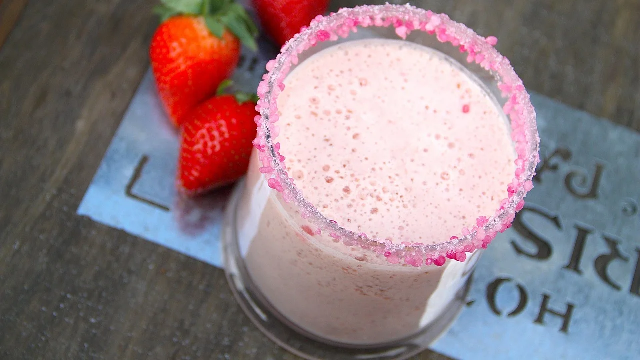Milkshake de morango cremoso servido em copo alto.