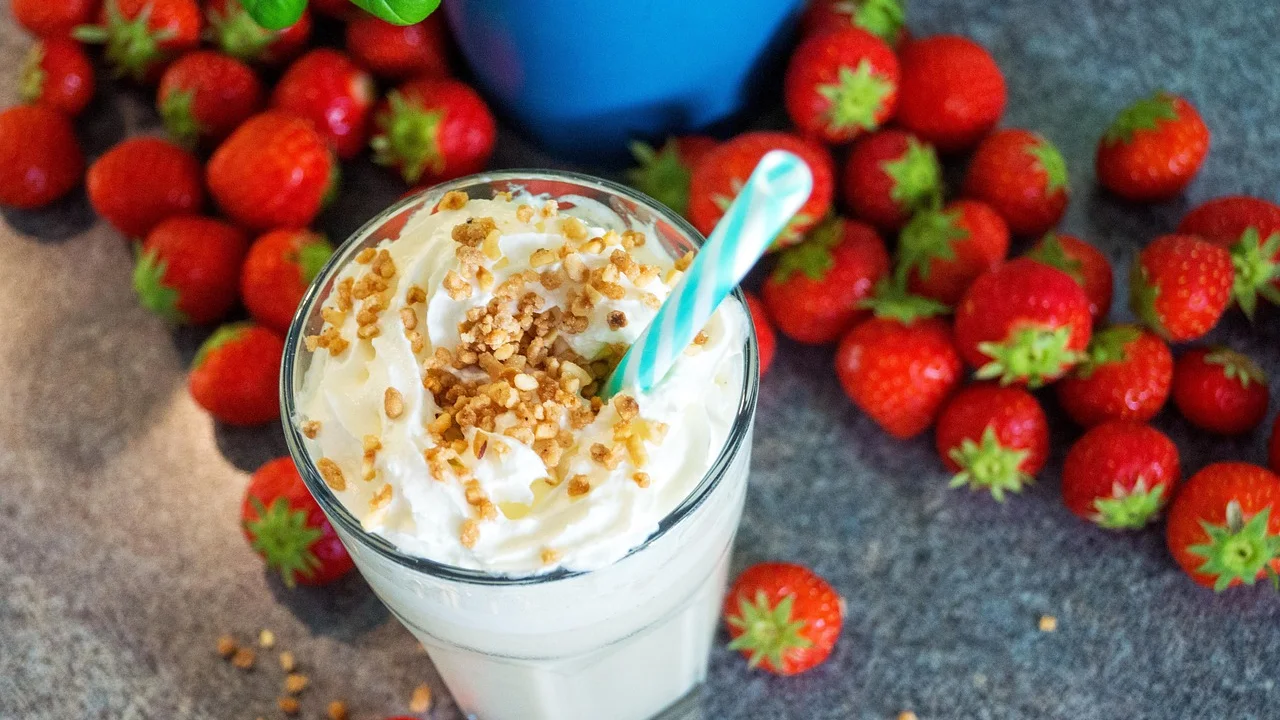 Milkshake de morango finalizado com chantilly e fruta.