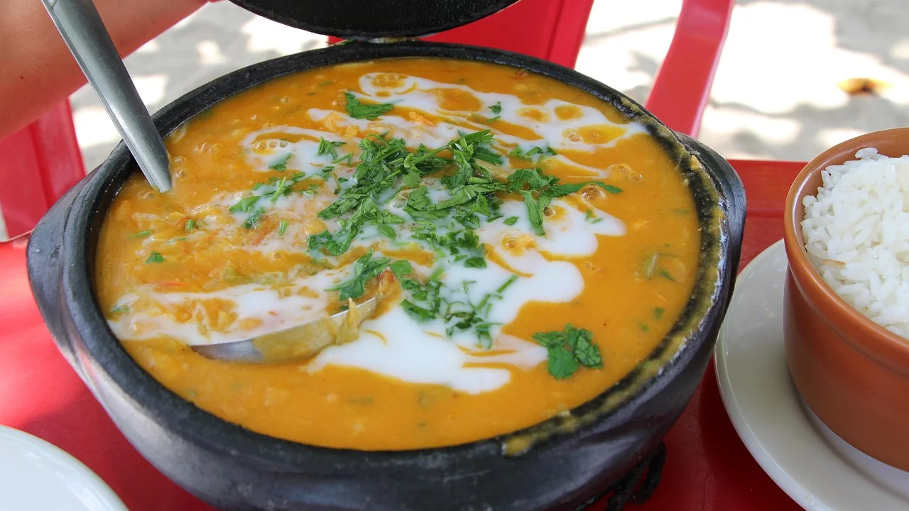Camadas de tomate, cebola e pimentões formando a base da moqueca.