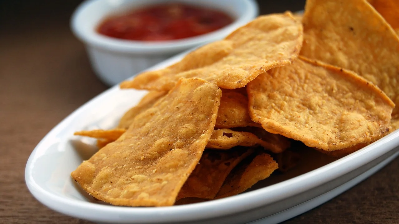 Travessa de nachos com queijo derretido e ingredientes frescos