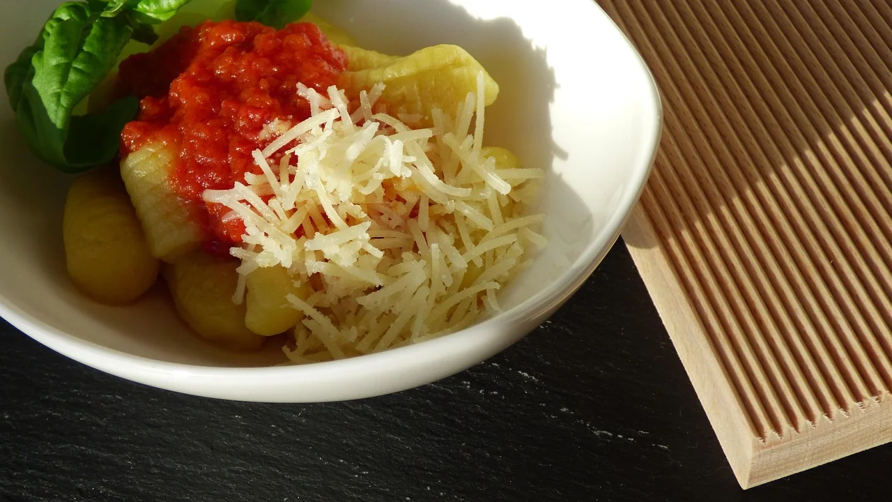Nhoque caseiro envolvido em molho de tomate e folhas de manjericão.