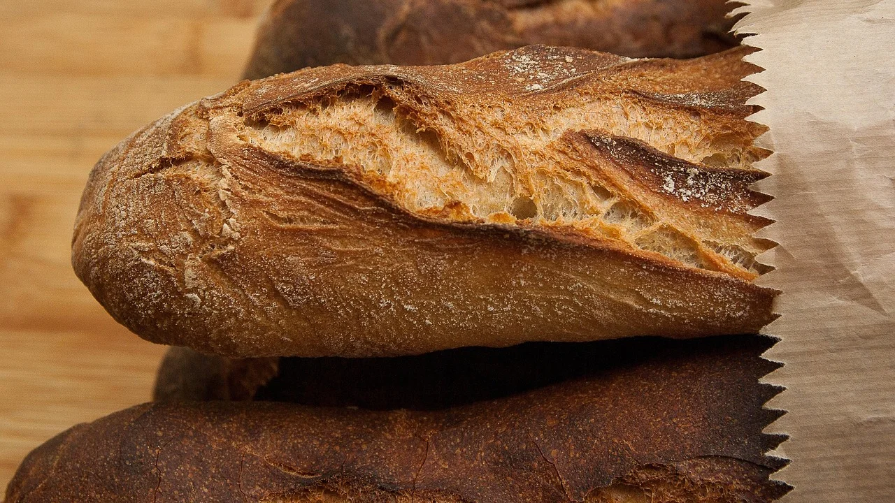 Massa de pão sendo sovada sobre uma bancada limpa.