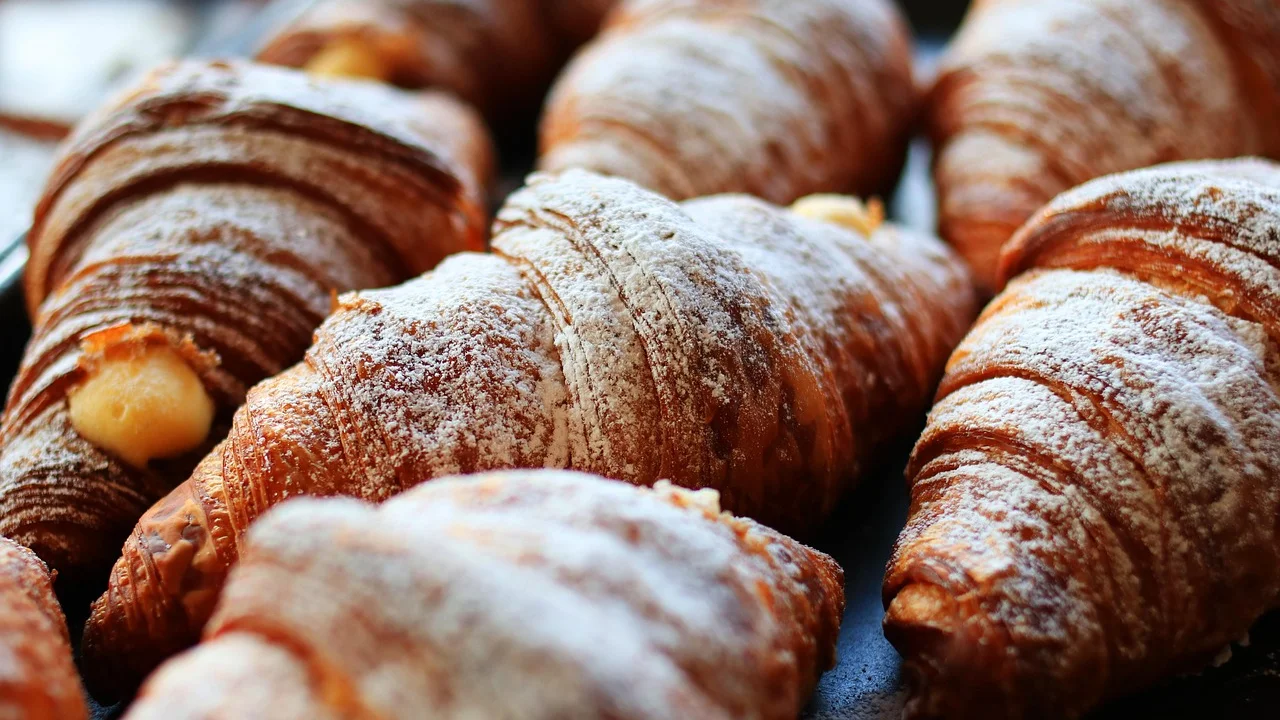 Pastéis de forno dourados dispostos em uma assadeira metálica.