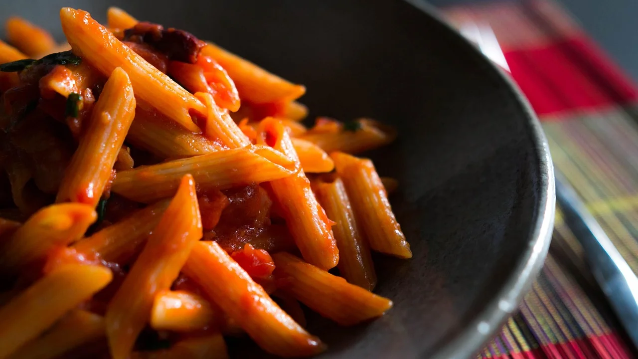 Prato de penne ao molho branco com ervas frescas por cima.