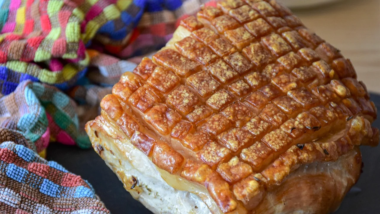 Fatias de pernil assado servidas com molho da assadeira.