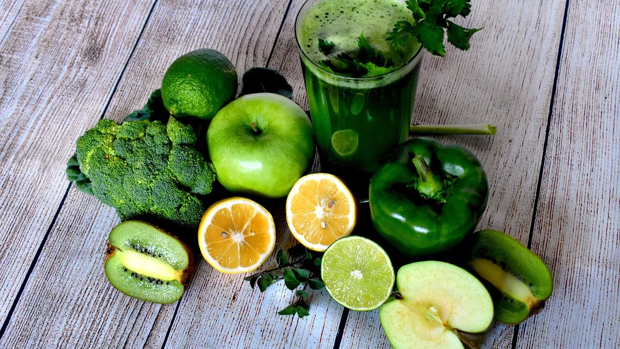 Copo de suco verde acompanhado de frutas frescas picadas.