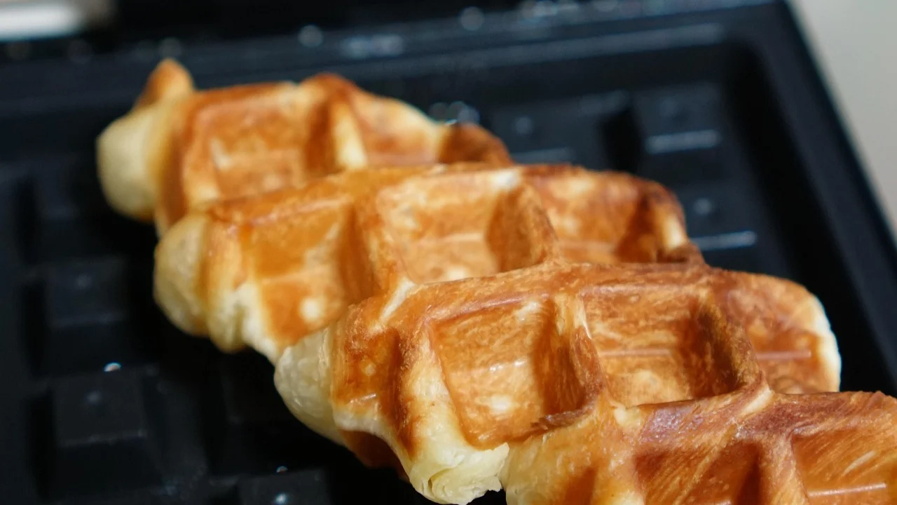 Waffles dourados recém-preparados em uma máquina doméstica.