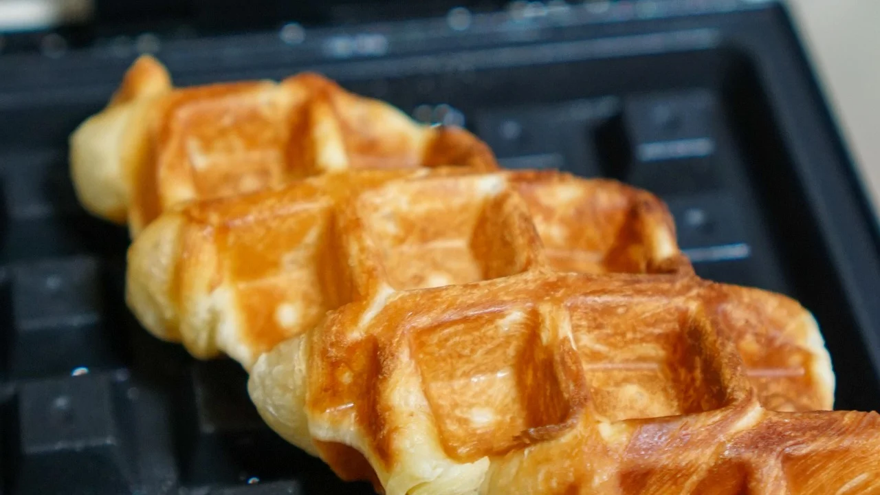 Massa de waffle sendo colocada no centro das placas aquecidas.