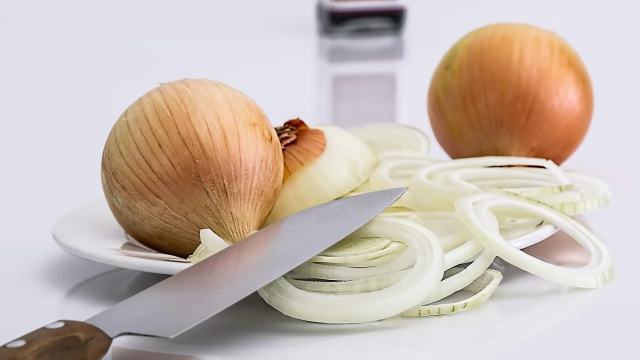 Cebola cortada ao meio sobre tábua firme de cozinha.