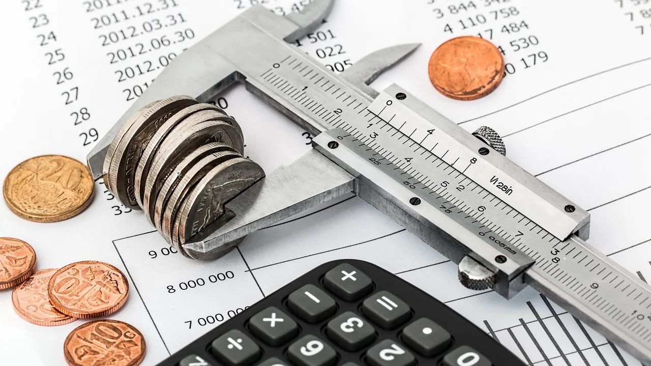Calculadora, caderno e contas organizados sobre uma mesa.